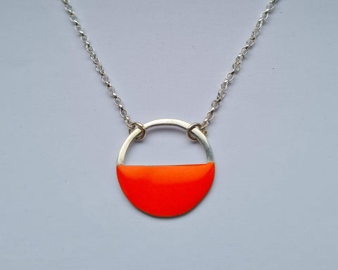 Necklace with a orange half-circle pendant on a gray background