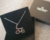 Silver necklace with 'LOVE' pendant on a black box with brand logo