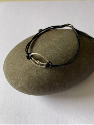 Bracelet with a black cord on a stone surface